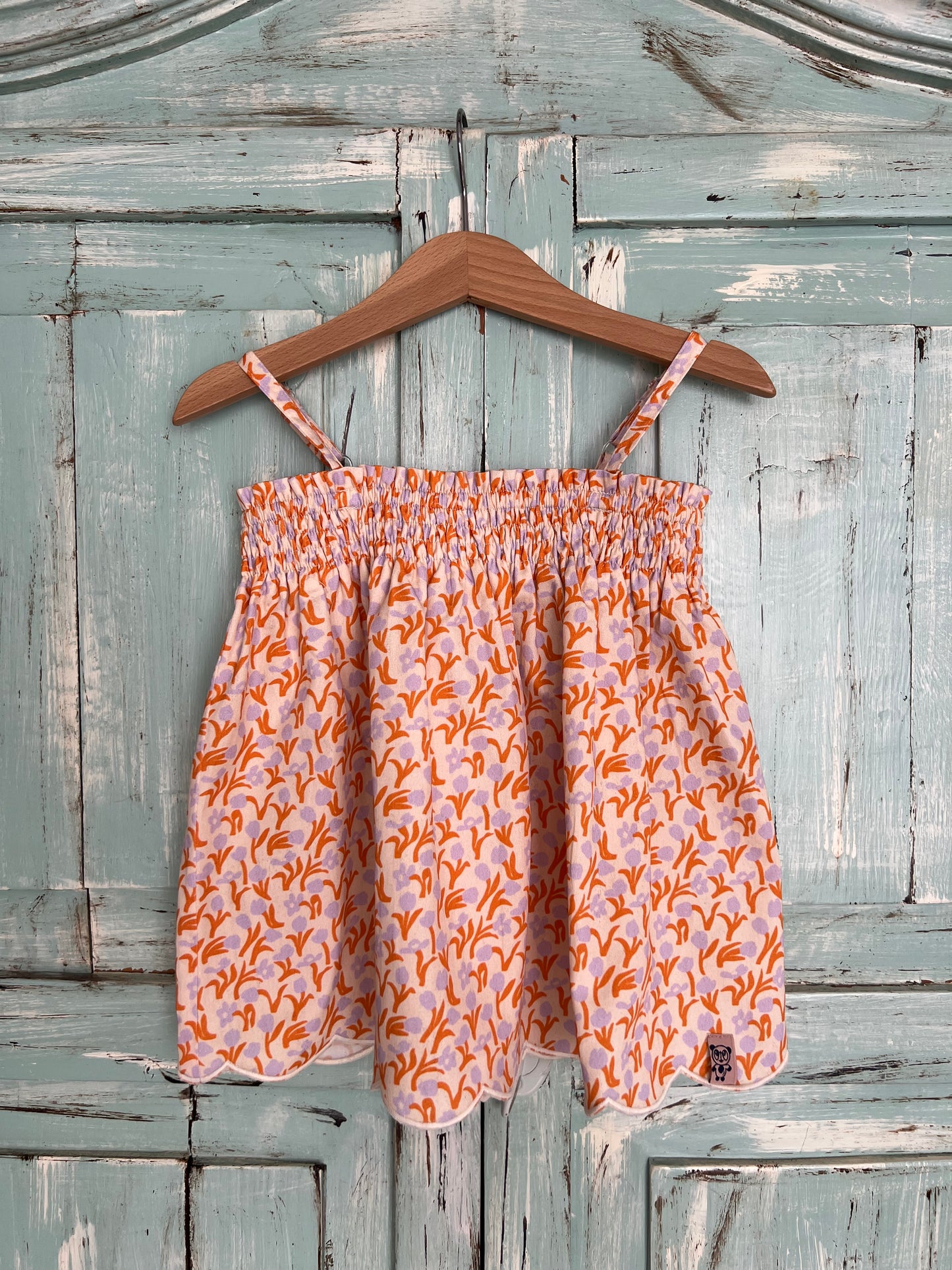soft organic cotton top for girls age 2 to 8 years old. flowery print with a soft pink base and orange and violet tulips, featuring a wavy embroidery line at the bottom, soft elastic at the chest and adjustable straps for a comfortable fit. Flowy silhouette.