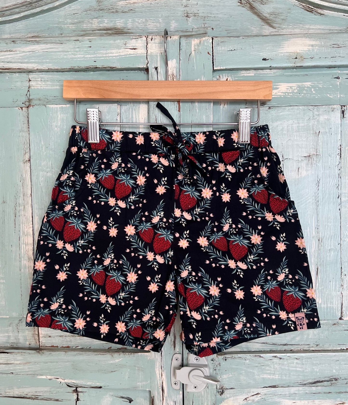 organic cotton shorts for kids age 2 to 9 years old, soft black base with strawberry and leaf print, relaxed fit, elastic waistband, and an adjustable drawstring.