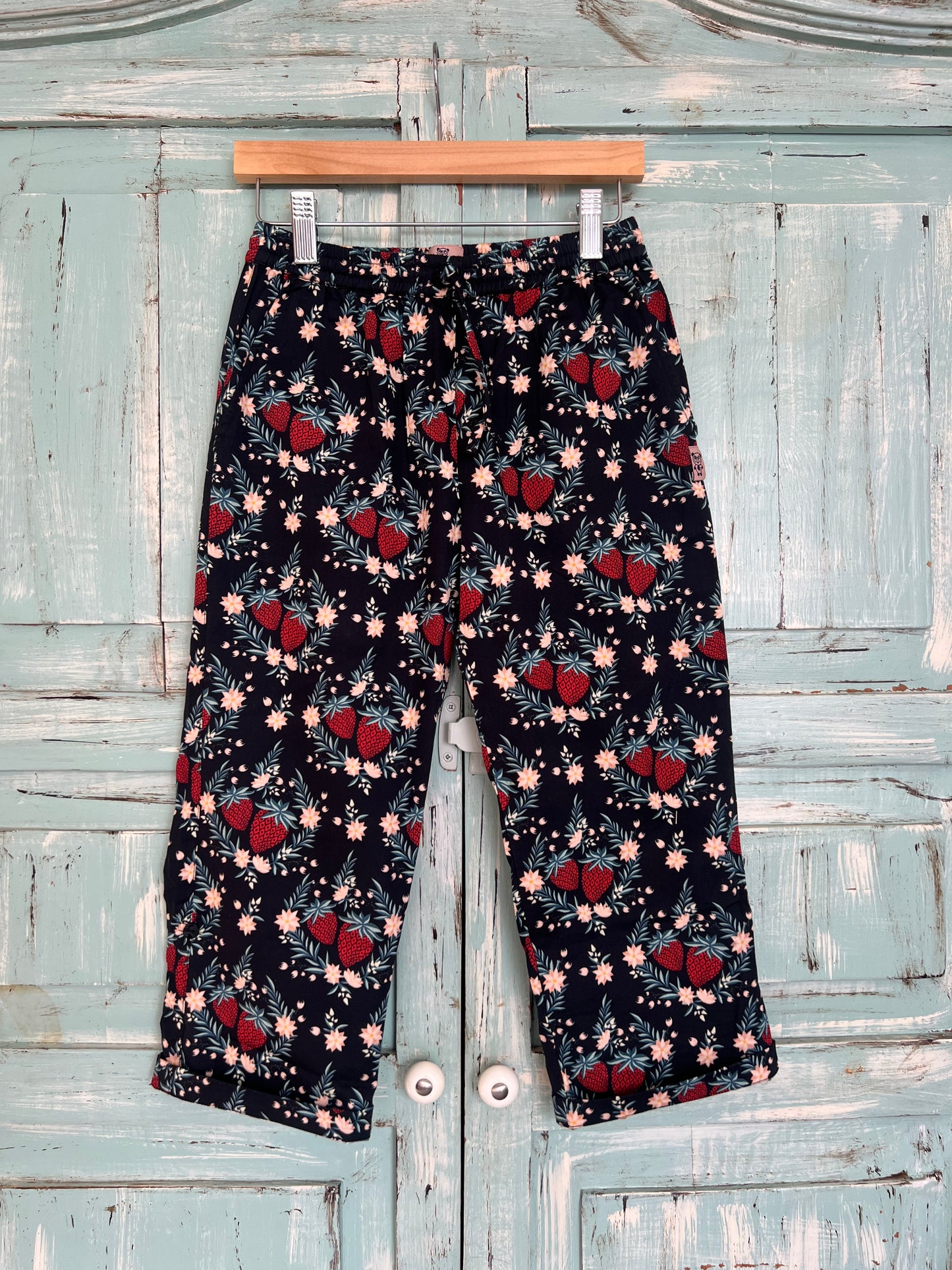 Organic cotton long pants, adjustable in length, with a red pink and green botanical print, black color base featuring strawberry, relaxed fit, pajama pants style, elastic waistband and adjustable drawstring.Age 2 to 8 years old