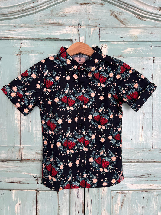 short-sleeves organic cotton button-up shirt for kids with black background and a vibrant print featuring strawberry motifs. Designed with a classic collar and relaxed fit for breathable comfort.