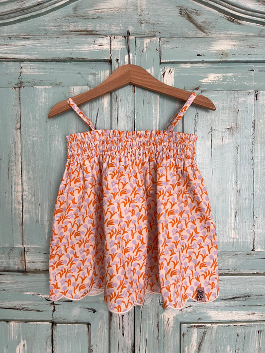soft organic cotton top for girls age 2 to 8 years old. flowery print with a soft pink base and orange and violet tulips, featuring a wavy embroidery line at the bottom, soft elastic at the chest and adjustable straps for a comfortable fit. Flowy silhouette.