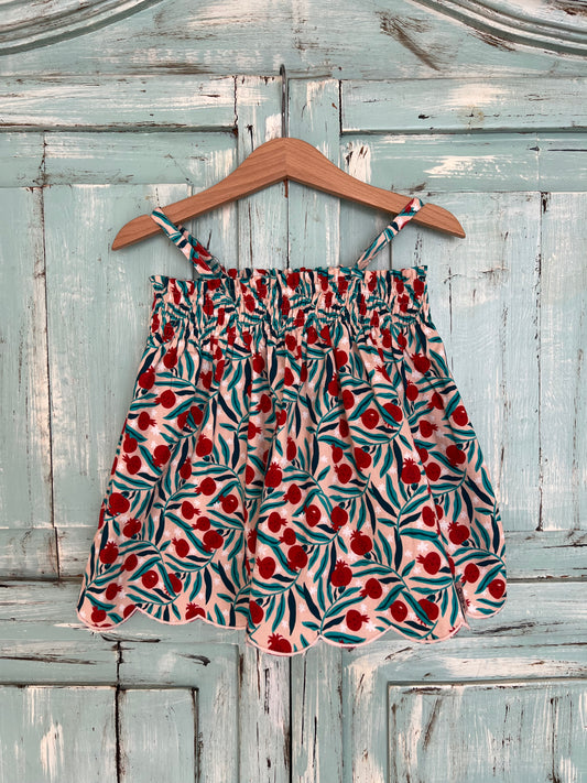 soft organic cotton top for girls age 2 to 8 years old. flowery print with a soft pink base and green and red pomegranate, featuring a wavy embroidery line at the bottom, soft elastic at the chest and adjustable straps for a comfortable fit. Flowy silhouette.