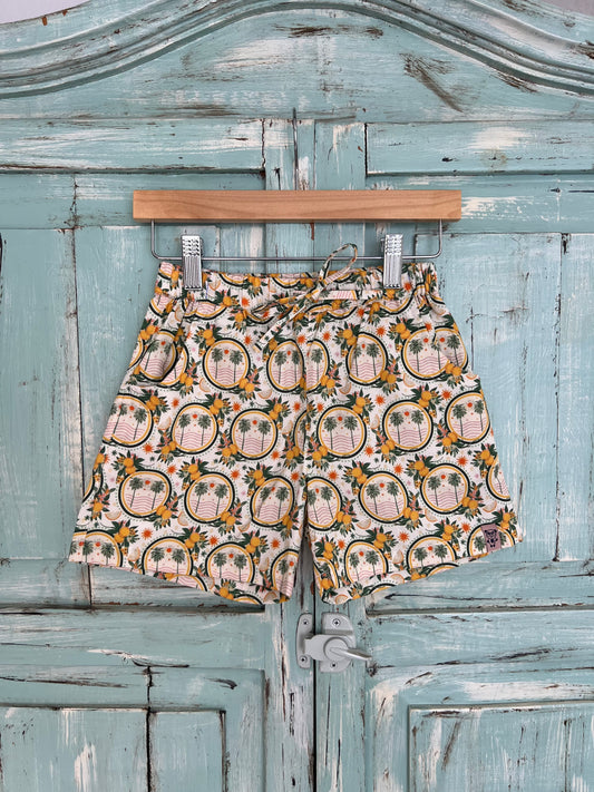 organic cotton shorts for kids age 2 to 9 years old, soft white base with palms and lemon and leaf print, relaxed fit, elastic waistband, and an adjustable drawstring.