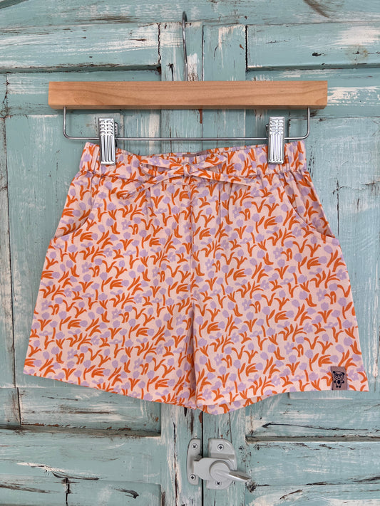 organic cotton shorts for kids age 2 to 9 years old, soft pink base with tulips and leaf and leaf print, orange and violet colors, relaxed fit, elastic waistband, and an adjustable drawstring.